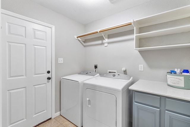 clothes washing area featuring cabinets, a textured ceiling, separate washer and dryer, and light tile patterned floors