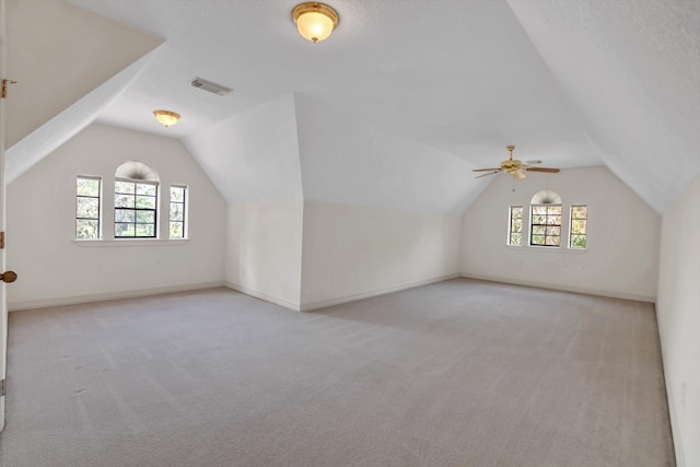 additional living space featuring light carpet, vaulted ceiling, and plenty of natural light