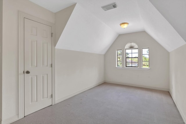 additional living space featuring lofted ceiling and light carpet