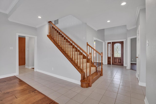 foyer entrance with ornamental molding and light tile patterned floors