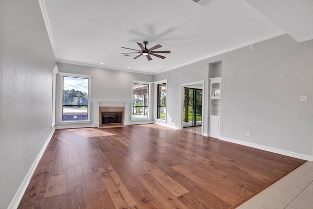 816 Lake Rd, Lake Jackson, TX 77566 - unfurnished living room featuring a ceiling fan, baseboards, a fireplace with flush hearth, wood-type flooring, and crown molding