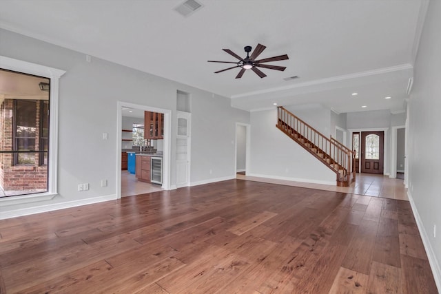 816 Lake Rd, Lake Jackson, TX 77566 - unfurnished living room with wine cooler, wood-type flooring, ceiling fan, baseboards, and stairs