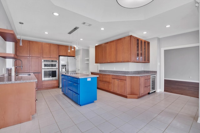 kitchen with appliances with stainless steel finishes, sink, a kitchen island, pendant lighting, and light stone counters