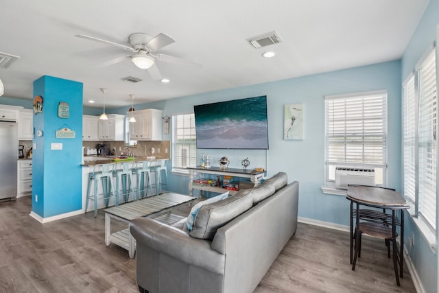 living room featuring sink, cooling unit, light wood-type flooring, and ceiling fan