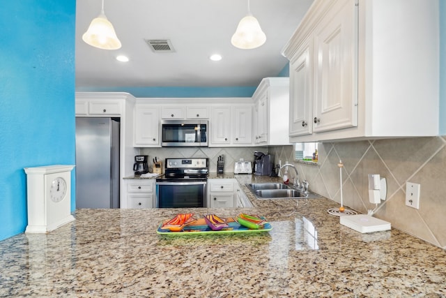 kitchen with sink, backsplash, stainless steel appliances, pendant lighting, and white cabinets