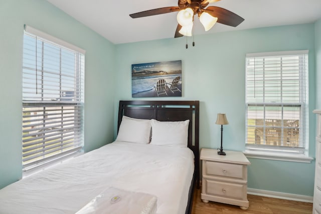 bedroom with multiple windows, wood-type flooring, and ceiling fan