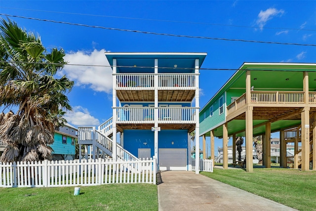 11218 Reagor Way, Galveston, TX 77554 - raised beach house featuring a garage, driveway, stairway, and a balcony