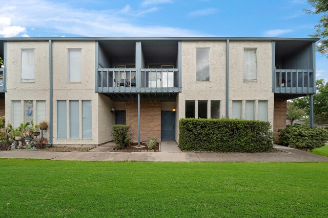 rear view of house with a balcony and a lawn