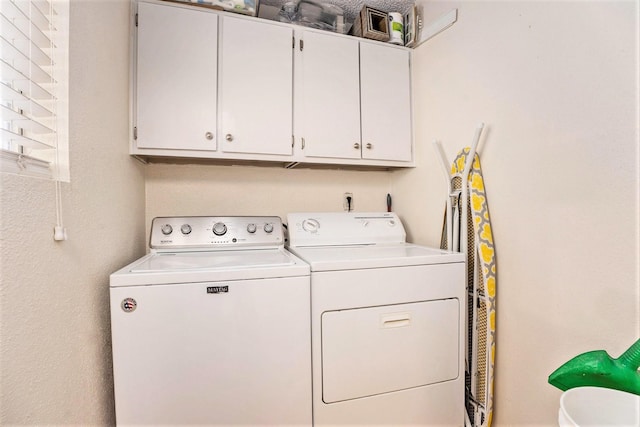 clothes washing area featuring cabinets and separate washer and dryer