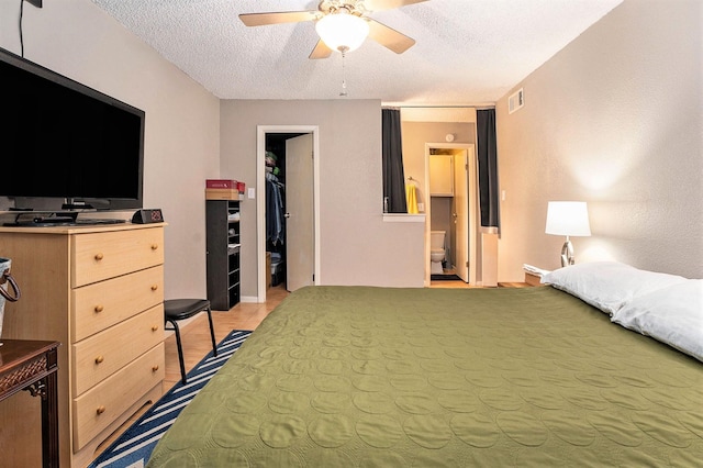 bedroom with ceiling fan, a textured ceiling, a spacious closet, connected bathroom, and a closet