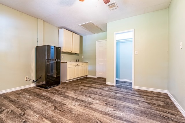 kitchen featuring dark wood-type flooring, ceiling fan, sink, and black fridge