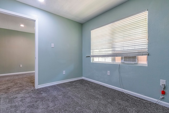 spare room featuring cooling unit and dark colored carpet