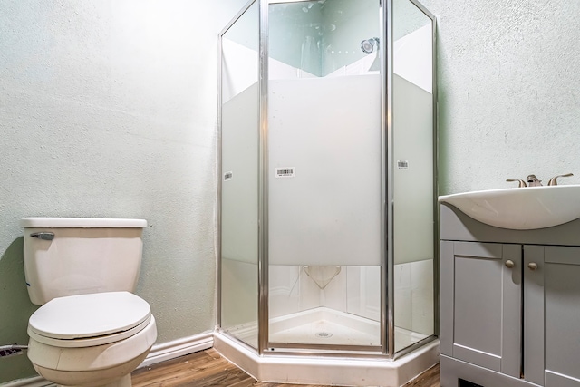 bathroom with vanity, toilet, hardwood / wood-style flooring, and a shower with shower door