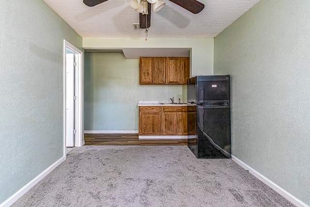 kitchen with light carpet, a textured ceiling, sink, and ceiling fan