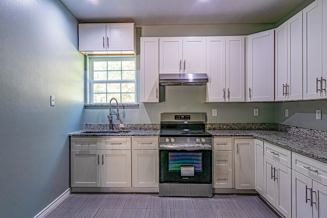 kitchen featuring sink, white cabinetry, stainless steel range oven, and dark stone counters