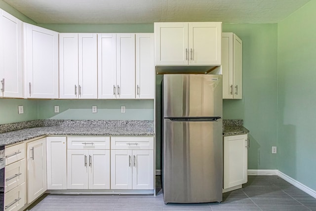 kitchen featuring white cabinetry, light stone countertops, and stainless steel fridge