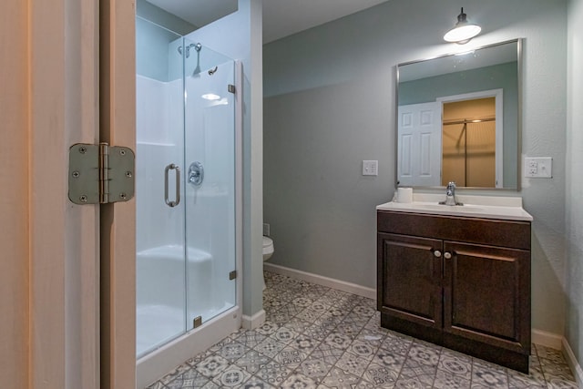 bathroom with a shower with door, vanity, toilet, and tile patterned floors