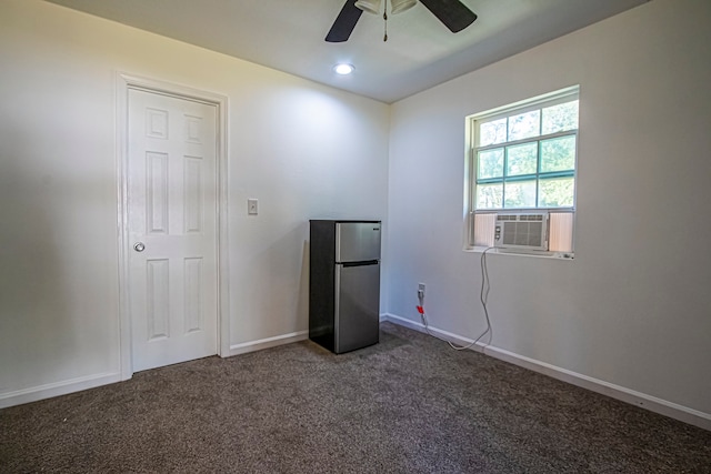 unfurnished bedroom with dark colored carpet, stainless steel fridge, and ceiling fan