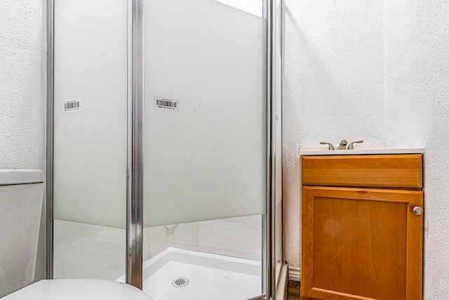 bathroom with toilet, a shower with shower door, and vanity