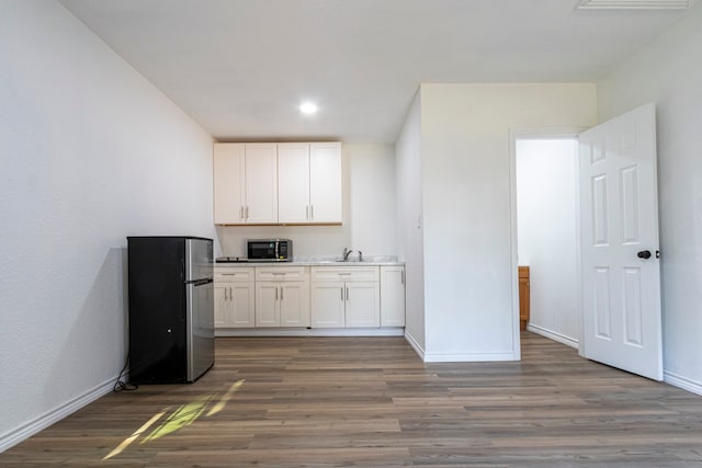 kitchen with sink, appliances with stainless steel finishes, dark hardwood / wood-style floors, and white cabinetry