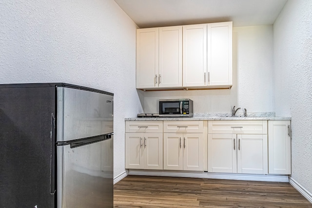 kitchen featuring white cabinets, light stone counters, dark hardwood / wood-style flooring, sink, and stainless steel appliances