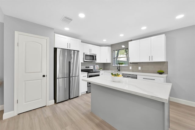 kitchen featuring light hardwood / wood-style floors, stainless steel appliances, a center island, and white cabinets