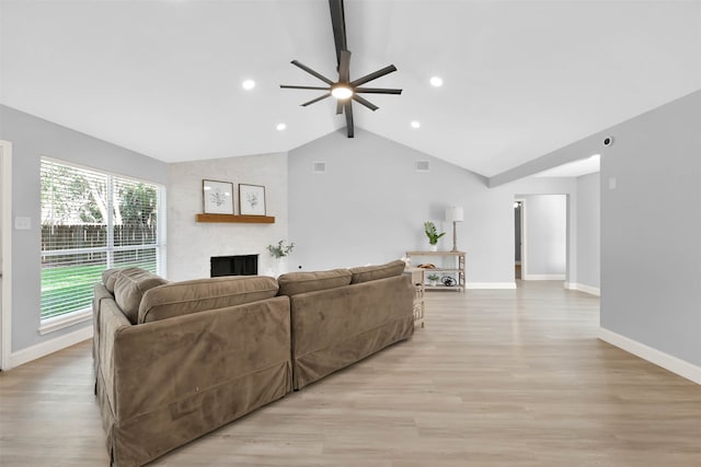 living room featuring light hardwood / wood-style flooring, lofted ceiling with beams, a large fireplace, and ceiling fan