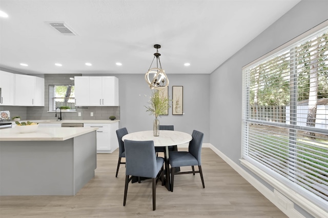 dining room with an inviting chandelier, sink, and light wood-type flooring