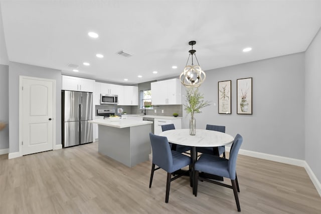 dining space featuring a chandelier, sink, and light wood-type flooring