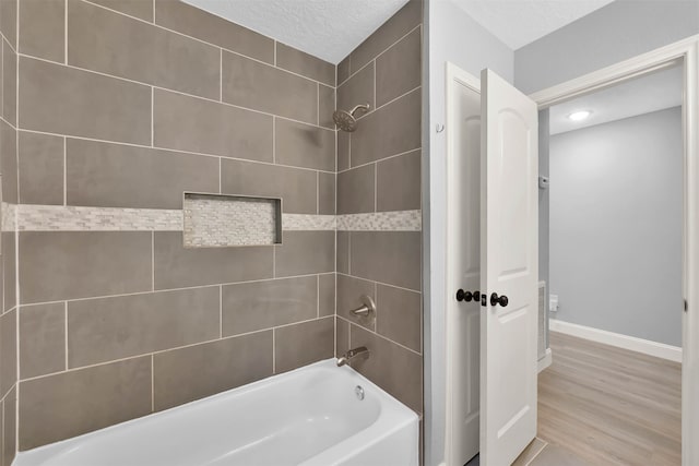 bathroom featuring tiled shower / bath, a textured ceiling, and wood-type flooring