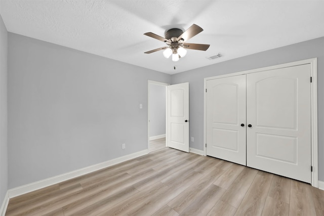 unfurnished bedroom featuring a closet, ceiling fan, a textured ceiling, and light wood-type flooring