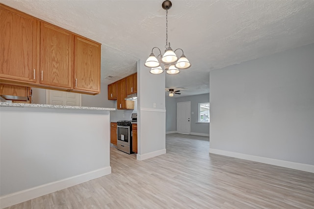 kitchen featuring a textured ceiling, light wood-type flooring, stainless steel range oven, ceiling fan with notable chandelier, and decorative light fixtures