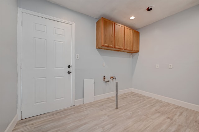 laundry area with hookup for a washing machine, cabinets, and light wood-type flooring