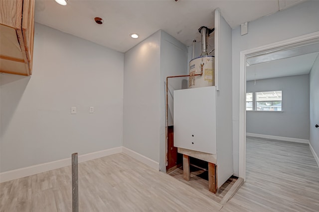 clothes washing area featuring gas water heater and light wood-type flooring