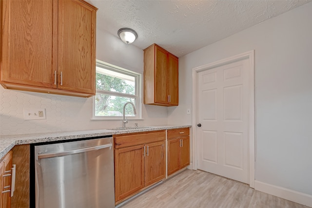 kitchen featuring dishwasher, light hardwood / wood-style flooring, sink, light stone counters, and a textured ceiling