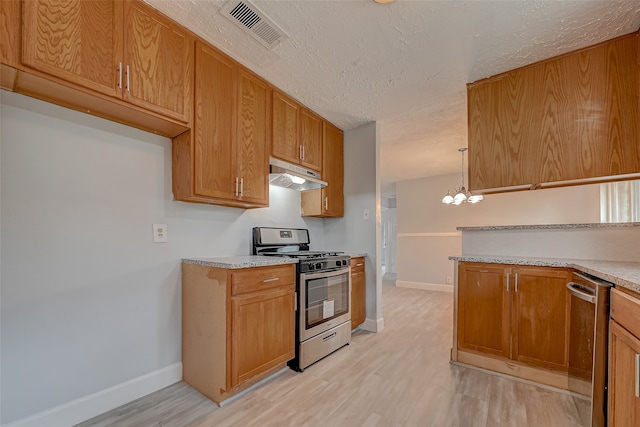 kitchen with appliances with stainless steel finishes, a textured ceiling, pendant lighting, light hardwood / wood-style flooring, and an inviting chandelier