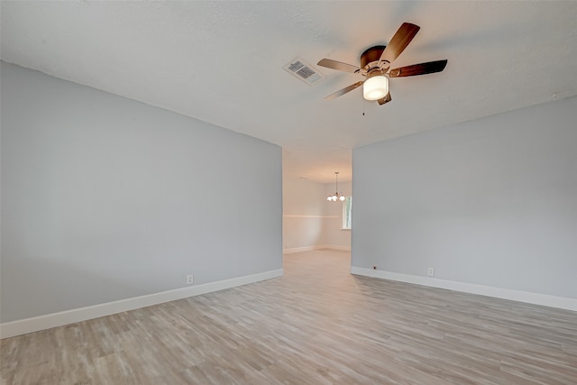 unfurnished room with light hardwood / wood-style floors and ceiling fan with notable chandelier