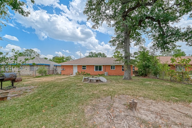 back of property with a yard and an outdoor fire pit