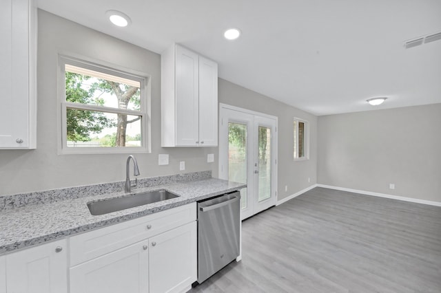 kitchen with white cabinets, light stone counters, stainless steel dishwasher, light hardwood / wood-style flooring, and sink