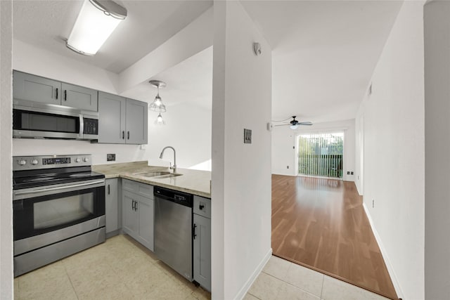 kitchen featuring stainless steel appliances, sink, gray cabinets, light stone counters, and light hardwood / wood-style floors