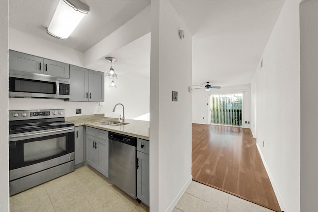 kitchen featuring a sink, light tile patterned flooring, gray cabinets, ceiling fan, and appliances with stainless steel finishes