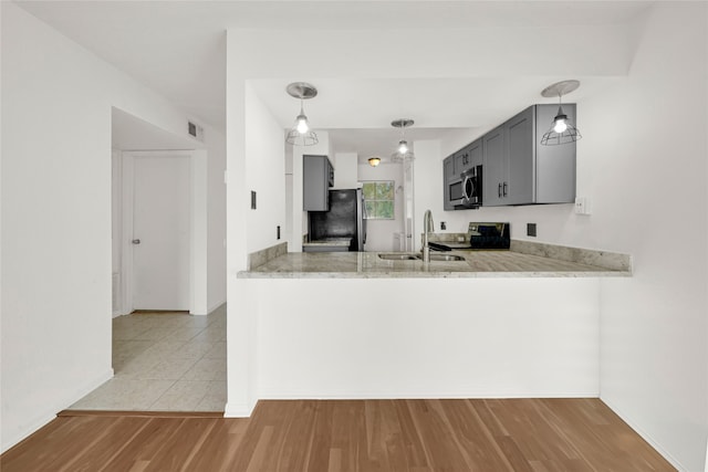 kitchen featuring light hardwood / wood-style floors, kitchen peninsula, sink, and stainless steel appliances