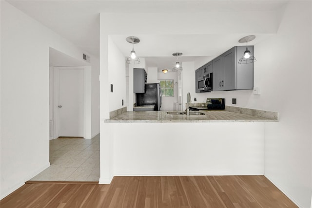 kitchen featuring a sink, pendant lighting, a peninsula, appliances with stainless steel finishes, and visible vents