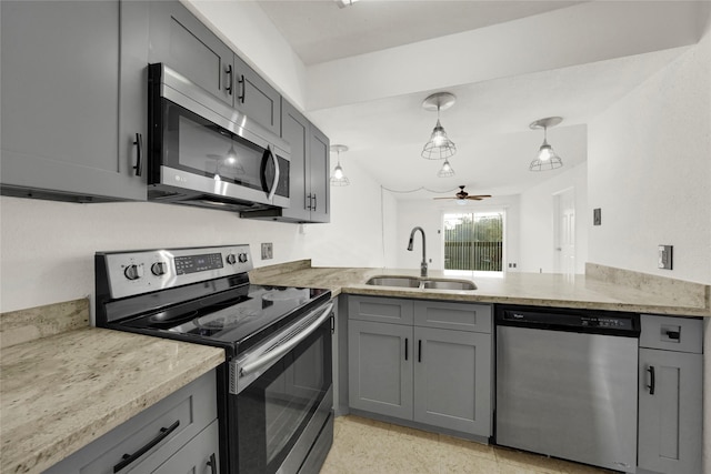 kitchen with light stone counters, a sink, gray cabinetry, appliances with stainless steel finishes, and ceiling fan