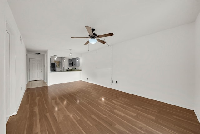 unfurnished living room with wood finished floors, a ceiling fan, and baseboards