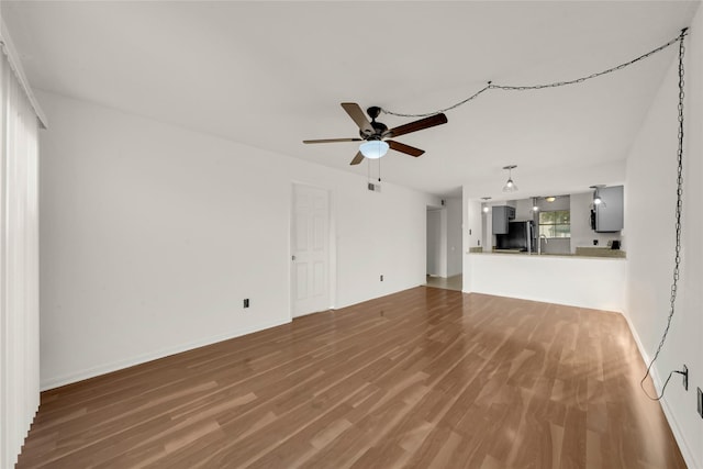 unfurnished living room featuring ceiling fan, baseboards, and wood finished floors