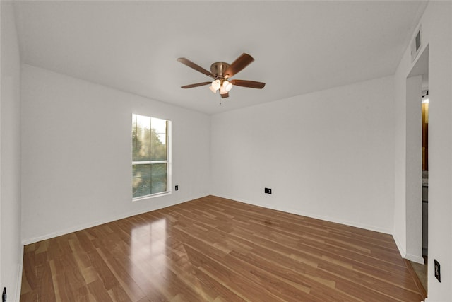 empty room featuring ceiling fan, baseboards, and wood finished floors
