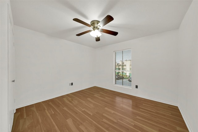 spare room with baseboards, wood finished floors, and ceiling fan