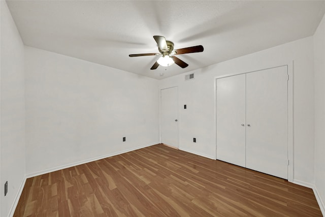 unfurnished bedroom featuring a textured ceiling, hardwood / wood-style flooring, a closet, and ceiling fan