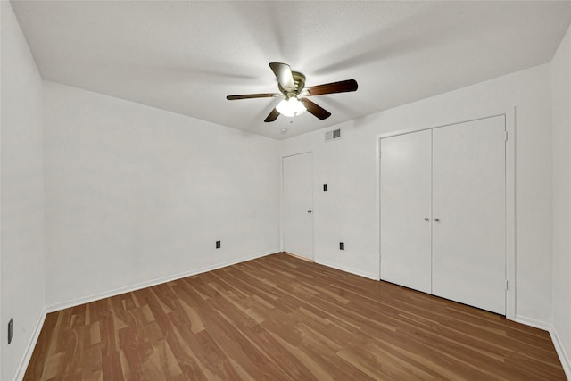 unfurnished bedroom with baseboards, visible vents, wood finished floors, a closet, and ceiling fan